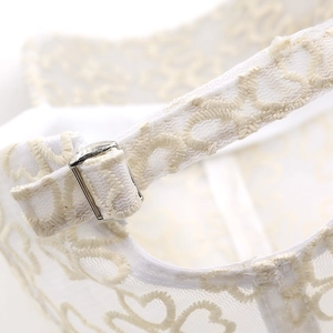 Detailed macro view of the adjustable metal buckle on this white lace baseball cap