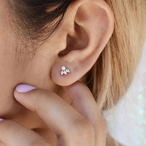 Detailed view of a gold leaf-shaped stud earring with pearls and marquise zircons
