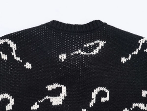 Macro view of black knit sweater featuring white abstract jacquard pattern and ribbed collar