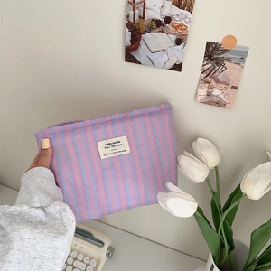 Close-up of striped canvas cosmetic bag with aesthetic fabric label in hand