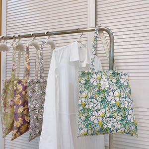 Borsa a spalla in tela a fiori in quattro fantasie vivaci con etichetta in tessuto bianco
