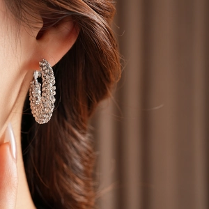 Close-up of sparkling rhinestone pavé silver hoop earrings on female model