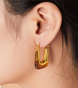 Close-up of retro U-shaped gold earrings with amber resin texture on a model