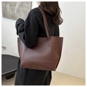 Detail view of large dark brown tote bag worn over the shoulder showing size and leather texture