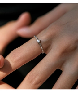Vue macro détaillée d'une bague coeur en argent avec anneau perlé portée au doigt