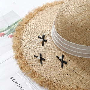 Fashionable raffia straw sun hat with black bows and pearl accents for summer travel