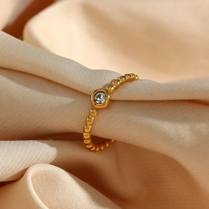 Macro shot of 18K gold plated beaded ring featuring a round clear zircon on beige silk