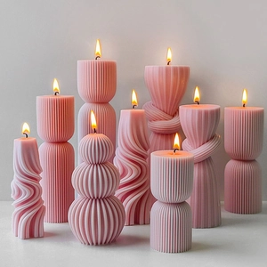 Pink striped pillar scented candles in artistic shapes burning on a white surface