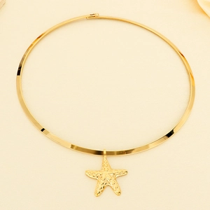 Flat lay of a gold stainless steel choker with a detailed starfish pendant on beige fabric