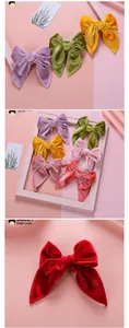 Détail de grandes barrettes à nœud en velours en plusieurs couleurs avec longs rubans