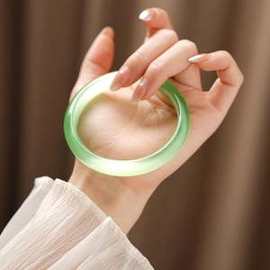 Detailed close-up of a light green cat eye stone bracelet on a woman wrist with silk luster
