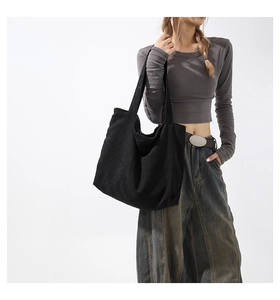 Black corduroy tote bag detail showing large capacity and soft textured fabric strap