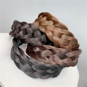 Three fishtail braided headbands in black and brown shades on a display stand