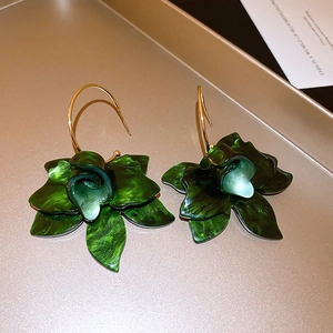 Macro shot of dark green resin flower earrings with marble texture on gold tray