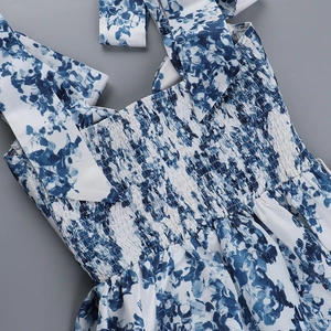 Détail d'une robe d'été à fleurs bleues avec bustier froncé et fines bretelles