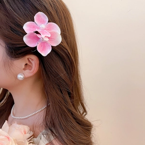 Close-up of pink flower hair clip with pearl center worn on brunette hair