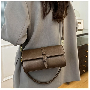 Dettaglio di una borsa a tracolla vintage marrone scuro con fibbia dorata su un blazer
