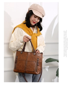 Detail of a brown PU leather tote bag with double zip pockets and cross-body strap