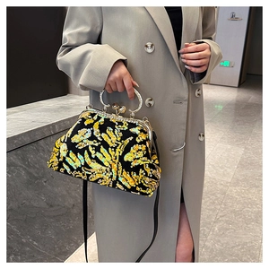 Close-up of a sequin shell bag with gold round metal handle and classic clasp closure
