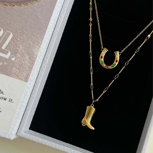 Golden horseshoe and cowboy boot necklace set with colorful zirconia on black velvet