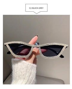 Close-up of narrow cat-eye sunglasses with rhinestone edges and dark grey lenses