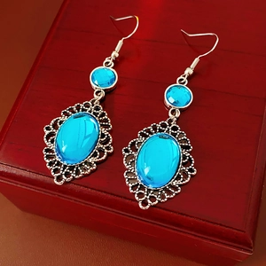 Macro shot of silver vintage earrings featuring oval blue resin and filigree lace details