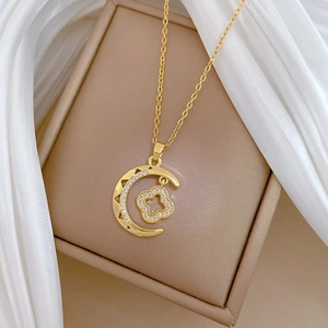 Macro detail of gold moon clover necklace with crystals on beige silk background