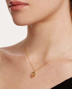 Close-up of gold necklace with crystal-embedded letter A pendant worn by a model