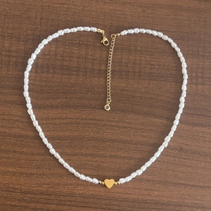 Bracciale di perle barocche con ciondolo a cuore su superficie in legno scuro