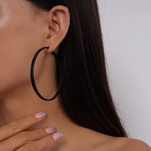 Close-up of model wearing a large black geometric leather hoop earring in dark style