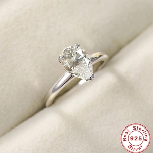 Macro shot of a pear-shaped diamond ring in 925 sterling silver on soft velvet padding