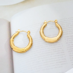 Detailed close-up of 18K gold-plated bamboo segment hoop earrings on a magazine