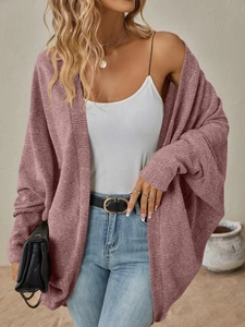 Dettaglio del cardigan in maglia rosa con trama fine e design delle maniche a pipistrello