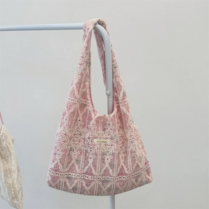 Close-up of pink fabric tote bag featuring white floral lace embroidery and a branded tag