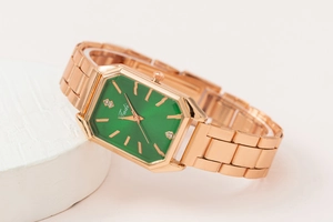 Macro view of octagonal green dial with rhinestones and rose gold metal watch strap