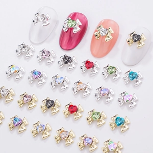 Close-up of alloy bow nail charms with colorful heart rhinestones on a white background