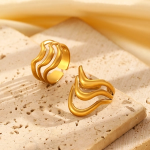 Detailed view of an irregular wave gold ring placed on a textured beige stone surface