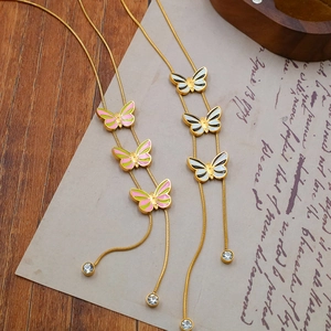 Detailed view of butterfly pendant with pink enamel and sparkling crystal drop on gold chain