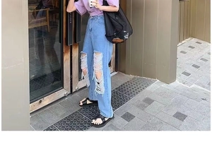 Detail of light blue ripped jeans with high-waist straight-leg fit and distressed knees