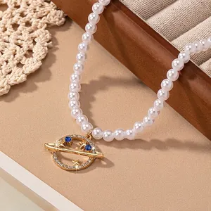Elegant pearl necklace with a gold planet Saturn pendant featuring blue zircons for women