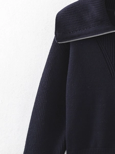 Detailed close-up of dark blue ribbed knit sweater with metal zipper and collar