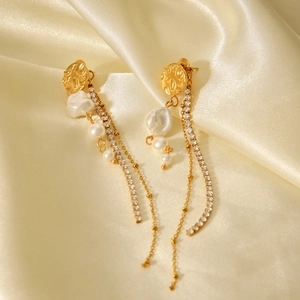 Gold long drop earrings with baroque pearls and rhinestone tassel on silk background