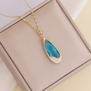 Gold necklace featuring a blue teardrop pendant with small diamonds and heart detail