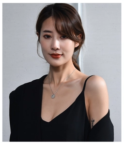 Silver clover necklace pendant on model neck featuring a fine metallic silver chain