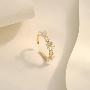 Close-up of golden adjustable ring with iridescent flower charms and rectangular crystals