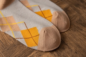 Macro detail of argyle pattern socks in grey and yellow over vintage wood background