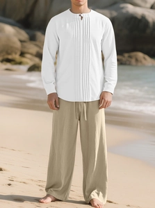 Détail d'une chemise en lin blanc et d'un pantalon beige à cordon sur une plage ensoleillée