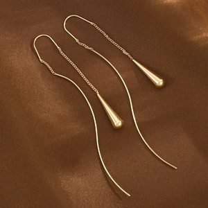 Elegant gold long tassel drop earrings with teardrop pendants on brown silk background