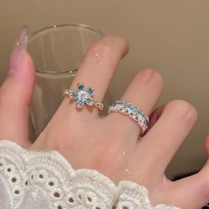 Detail of blue flower ring and lace band set with crystals worn on a finger