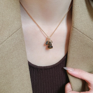 Close-up of a double tiger eye gourd pendant on a gold chain worn by a female model